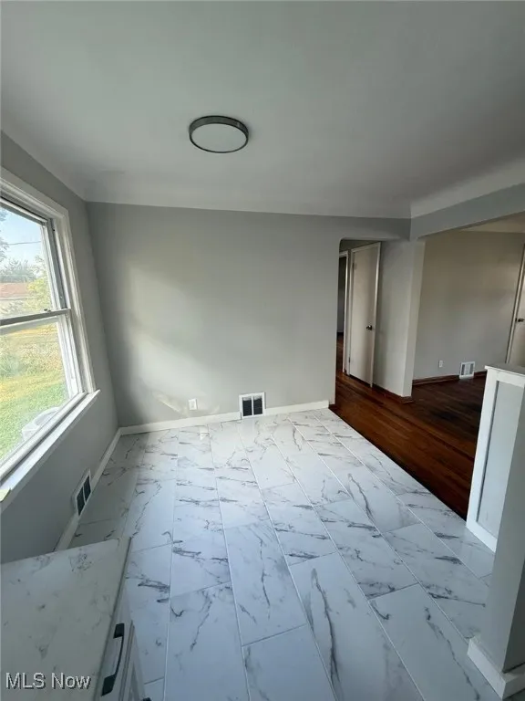 Unfurnished room with baseboards and marble look tile flooring