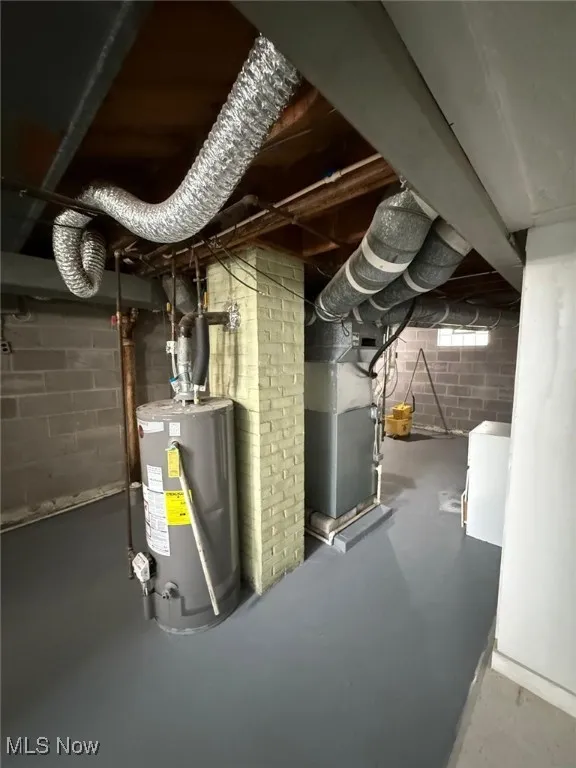 Unfinished basement featuring water heater, washer / dryer, and heating unit