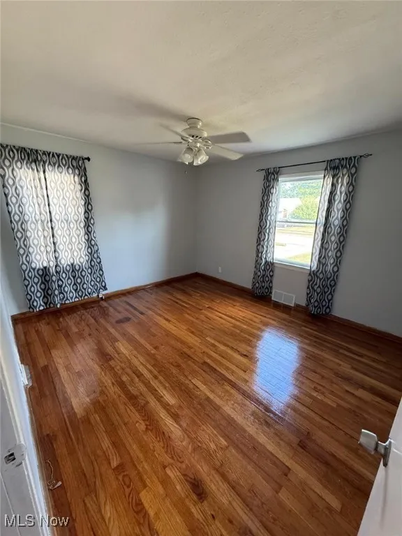 Spare room with wood finished floors, ceiling fan, and a textured ceiling
