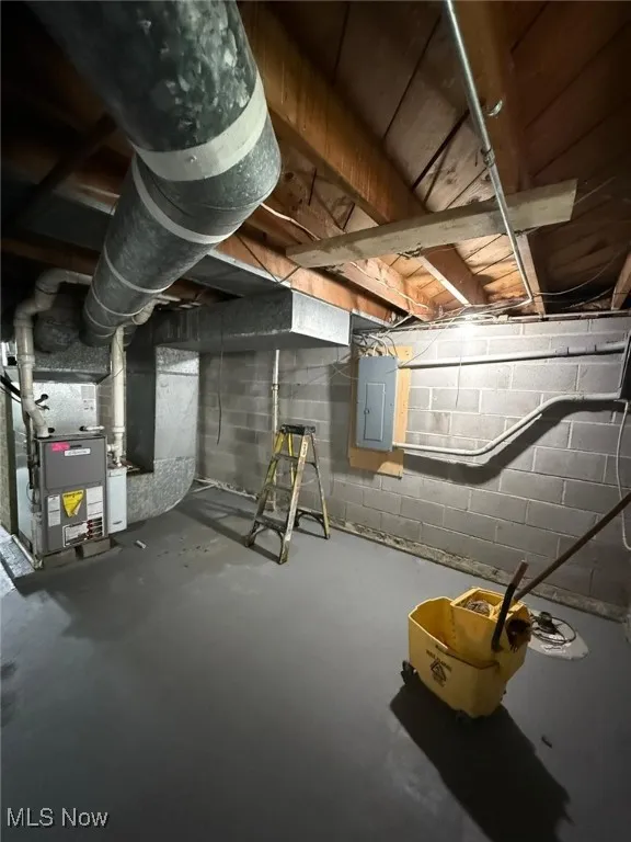 Unfinished below grade area featuring electric panel and heating unit