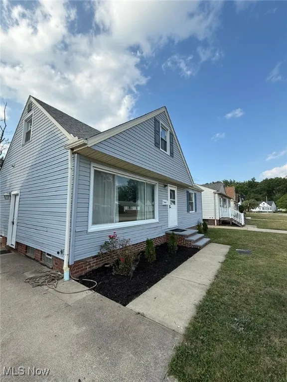Bungalow-style home featuring roof with shingles and a front yard
