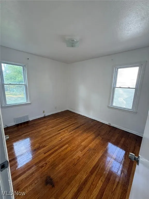 Unfurnished room featuring dark wood finished floors and a textured ceiling