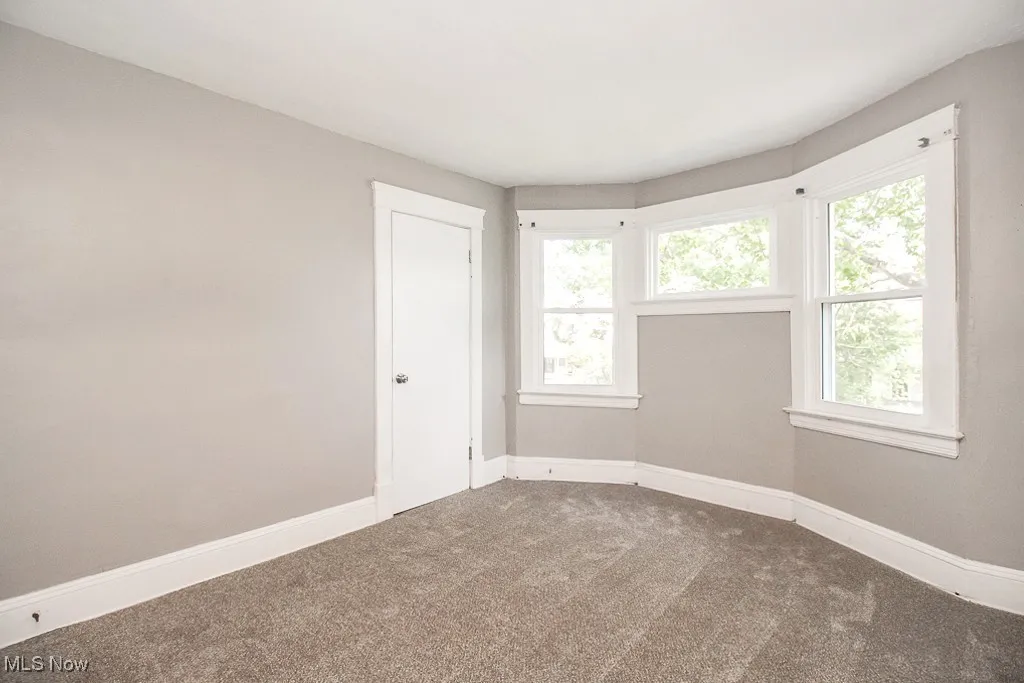 Spare room featuring carpet and baseboards