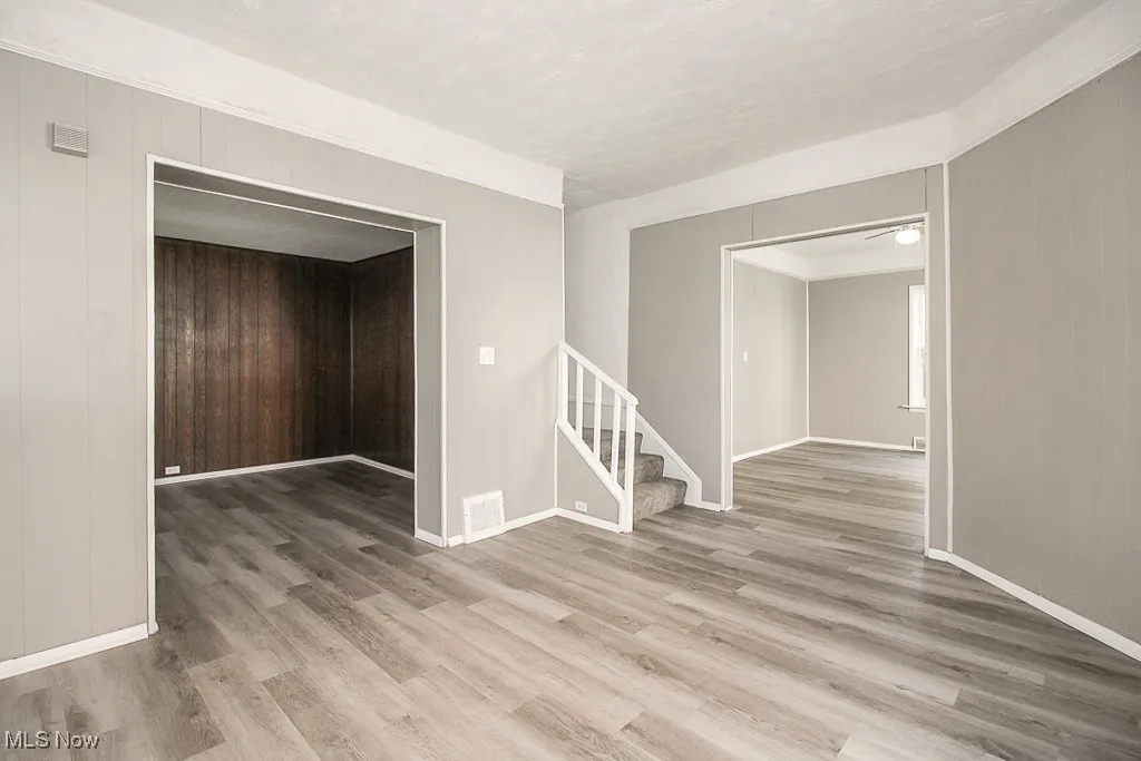 Spare room with stairs, wood walls, and light wood-style floors