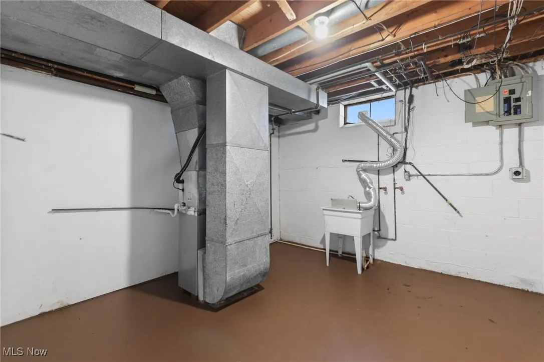 Below grade area featuring heating unit and electric panel