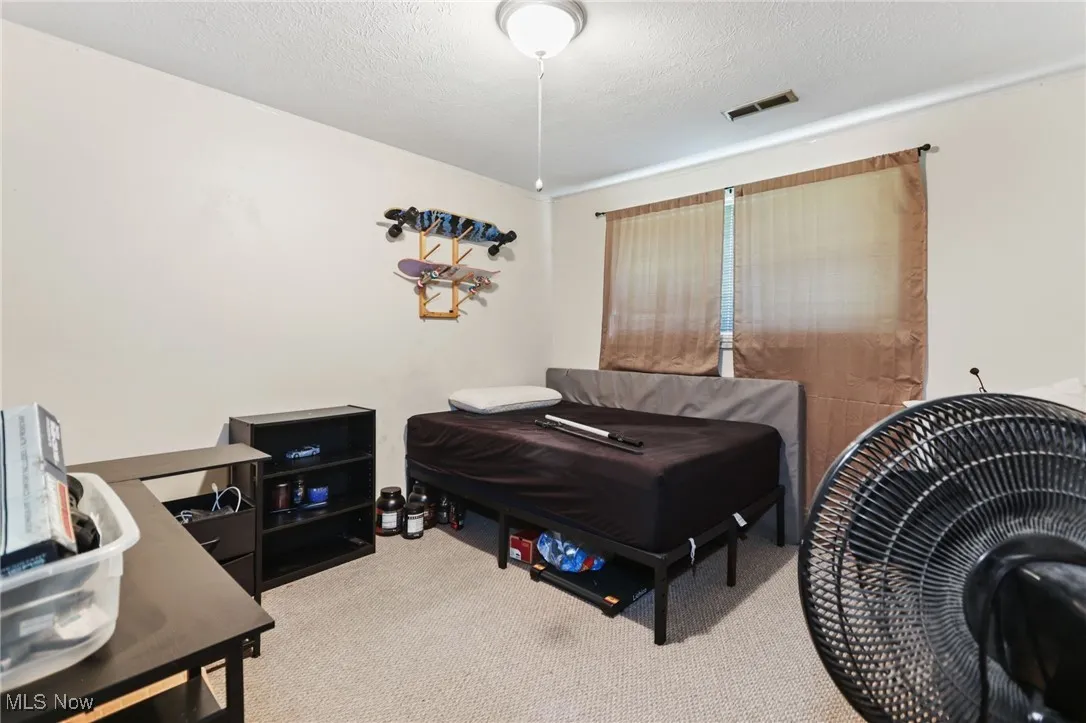 Bedroom featuring light colored carpet and a textured ceiling
