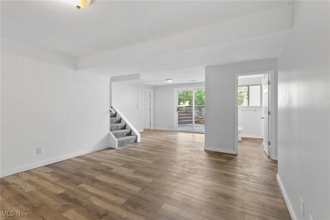 Unfurnished living room with stairway and wood finished floors