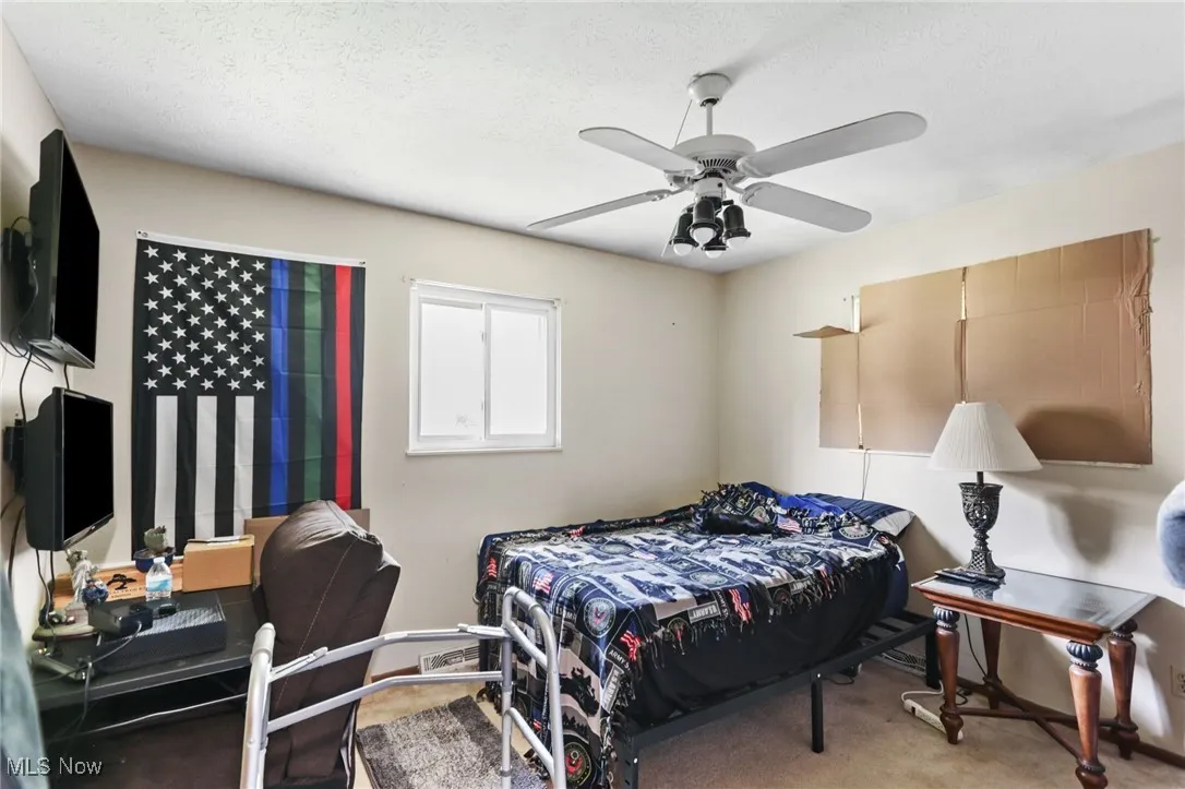 Carpeted bedroom featuring ceiling fan and a textured ceiling