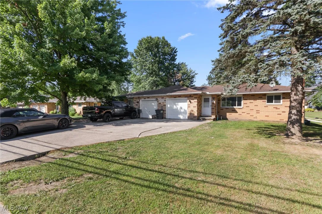 Ranch-style house featuring a garage, concrete driveway, brick siding, and a front yard