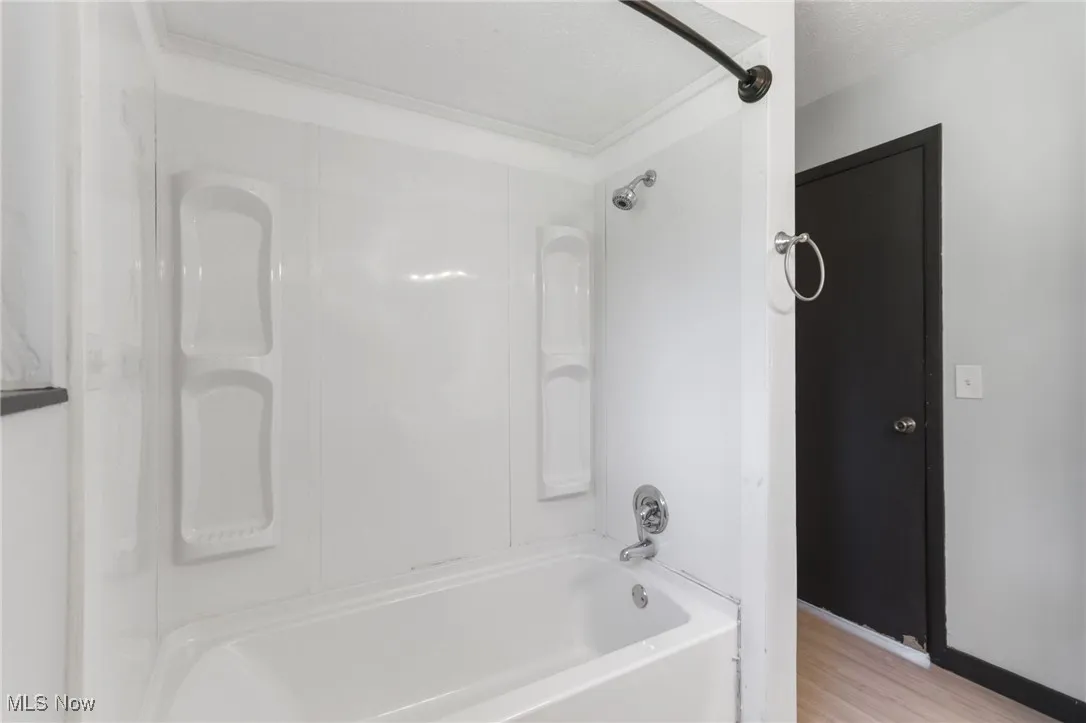 Bathroom featuring shower / bath combination, light wood finished floors, and a textured ceiling