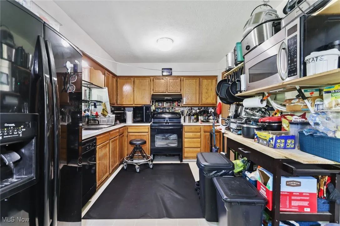 Kitchen with black appliances, light countertops, and brown cabinets