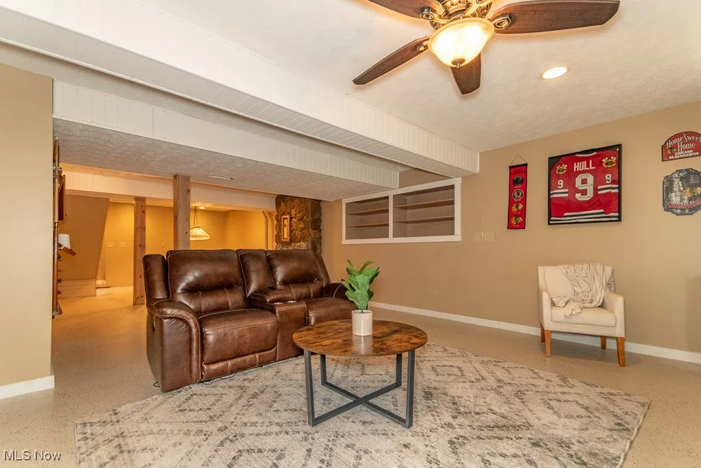 Living room featuring dark speckled floor, a ceiling fan, and recessed lighting