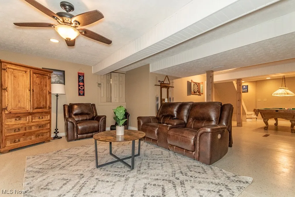 Living room featuring pool table, a ceiling fan, and a textured ceiling