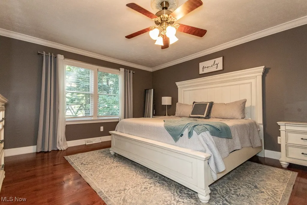 Bedroom featuring ornamental molding, dark wood-style flooring, and a ceiling fan