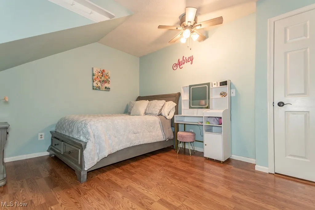 Bedroom with wood finished floors, a ceiling fan, and lofted ceiling
