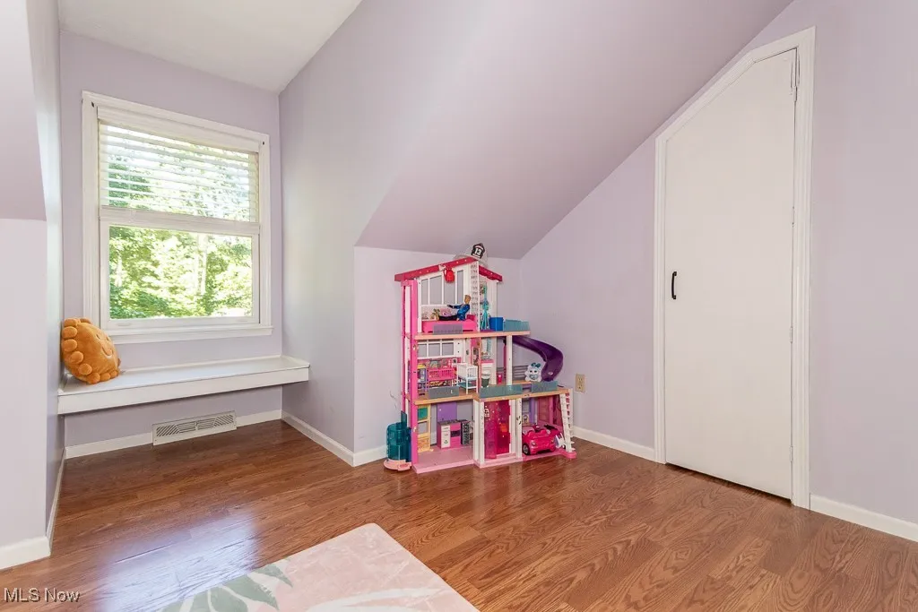Recreation room featuring wood finished floors and lofted ceiling