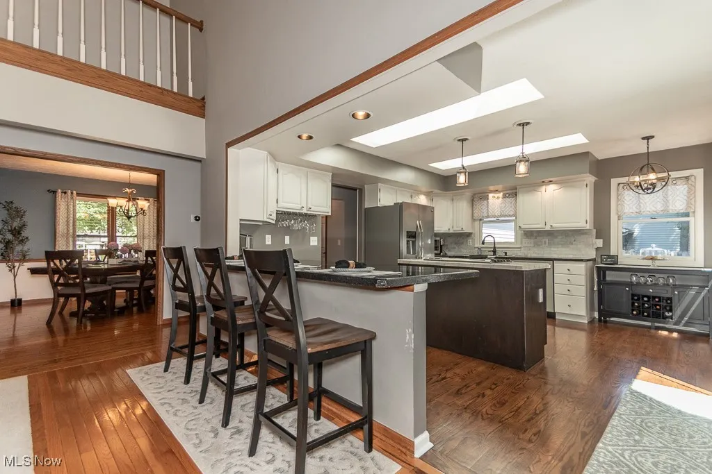Kitchen with a chandelier, dark wood-style flooring, a breakfast bar area, and pendant lighting