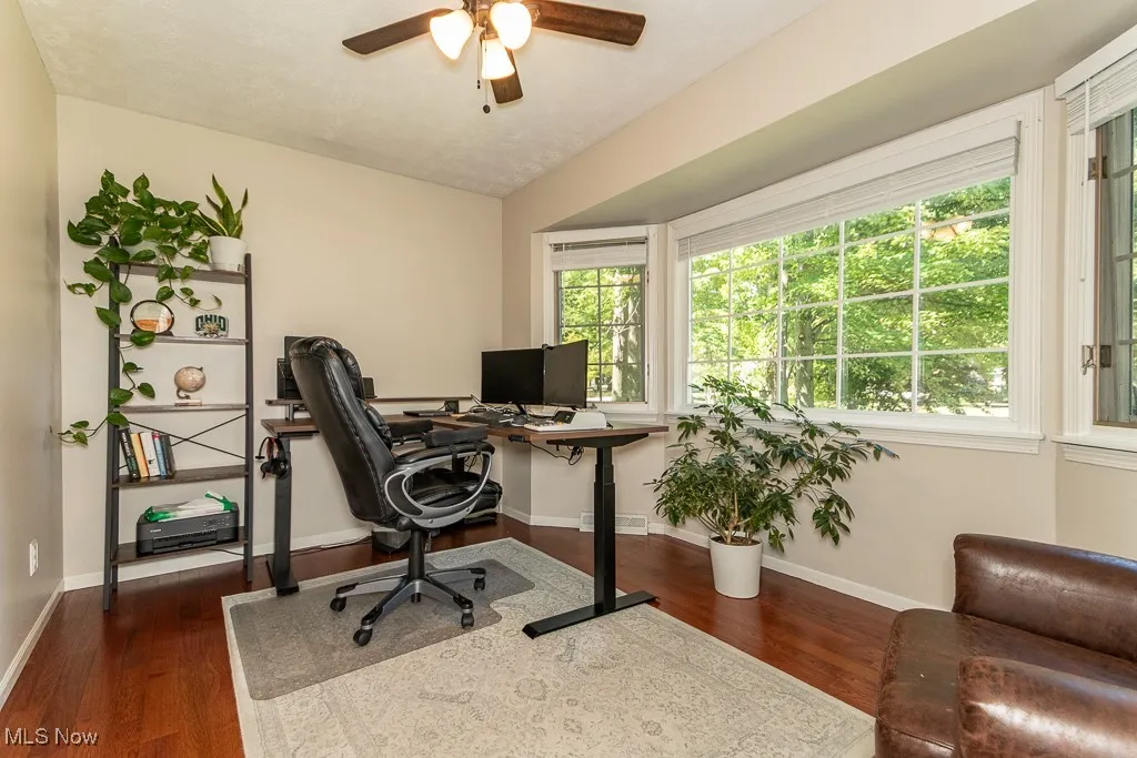 Office area featuring dark wood-style floors and ceiling fan