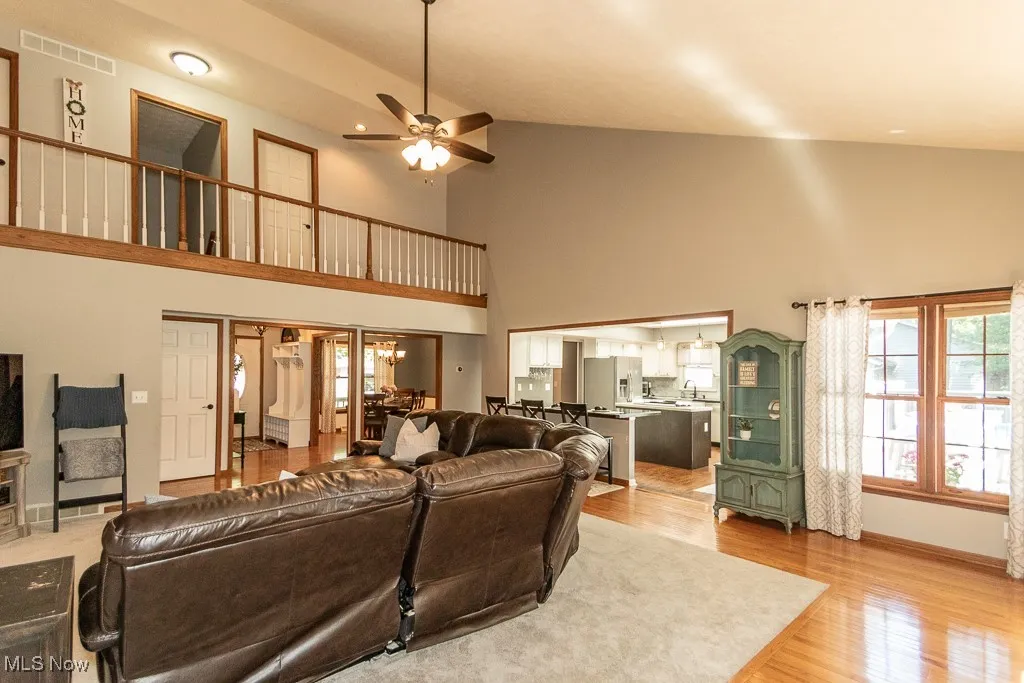 Living area featuring high vaulted ceiling, light wood-style floors, and ceiling fan