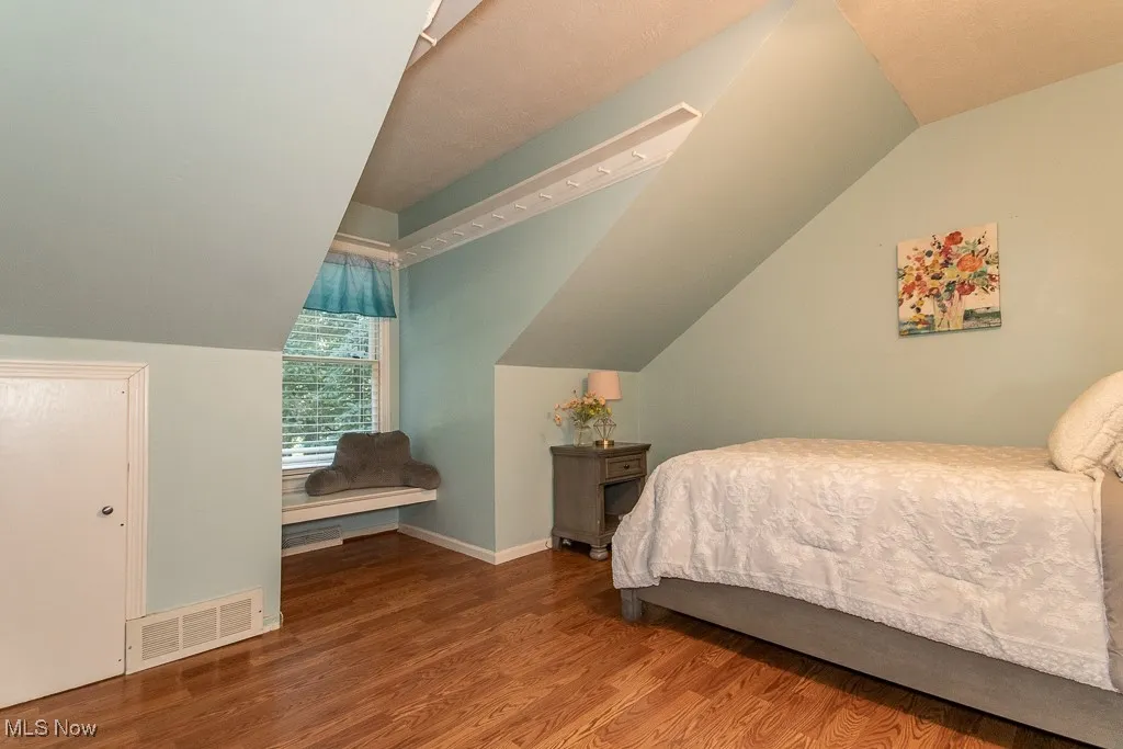 Bedroom featuring wood finished floors and vaulted ceiling