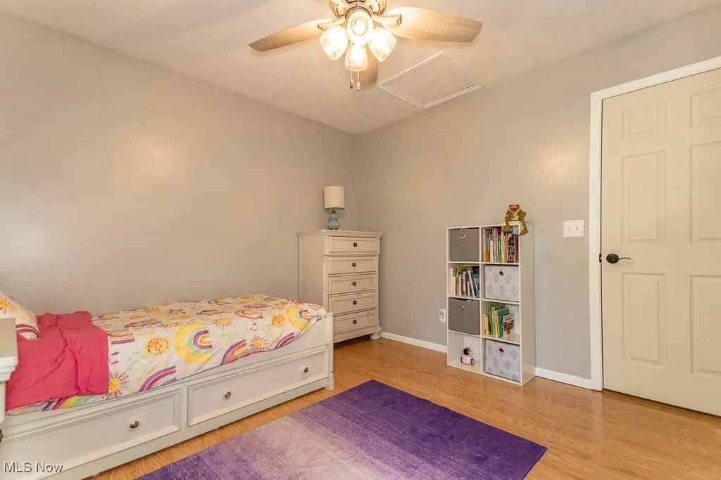 Bedroom featuring light wood-style flooring, attic access, and ceiling fan