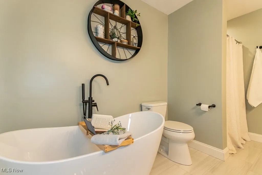 Full bath with a freestanding bath, tile patterned floors, and a shower with curtain