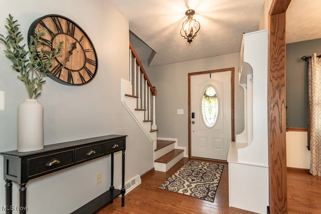 Entrance foyer featuring dark wood finished floors, a textured ceiling, and stairway