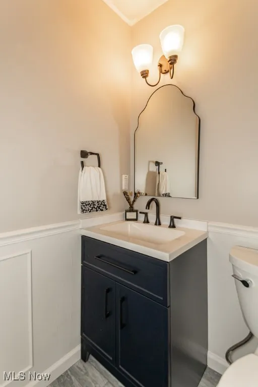Half bath featuring vanity and a wainscoted wall