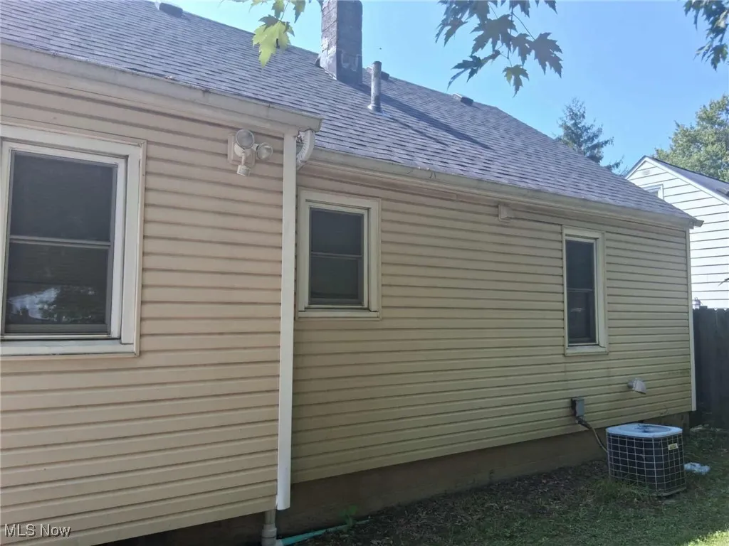 View of side of property with a shingled roof and a chimney