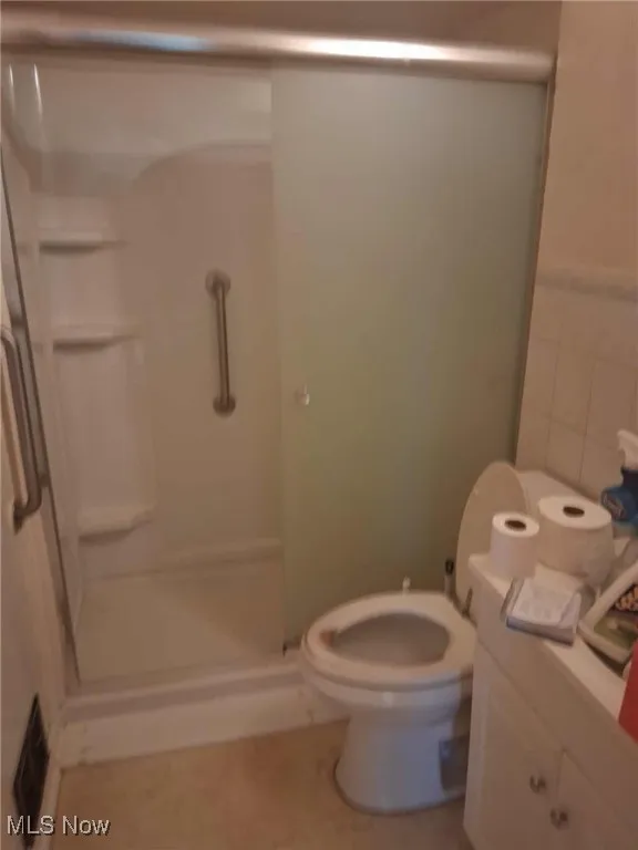 Full bath with a shower stall, tile walls, and vanity