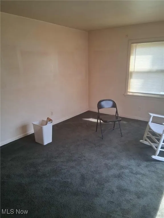 Unfurnished room with dark carpet and baseboards