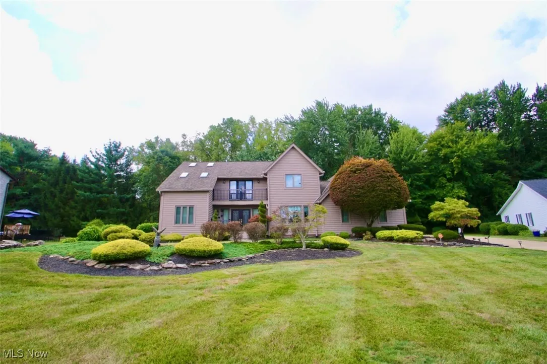 View of front of house featuring a balcony and a lovely front lawn