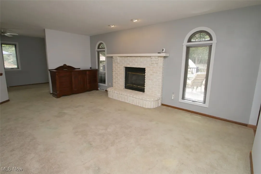 Family Room with light carpet, a fireplace, and a ceiling fan