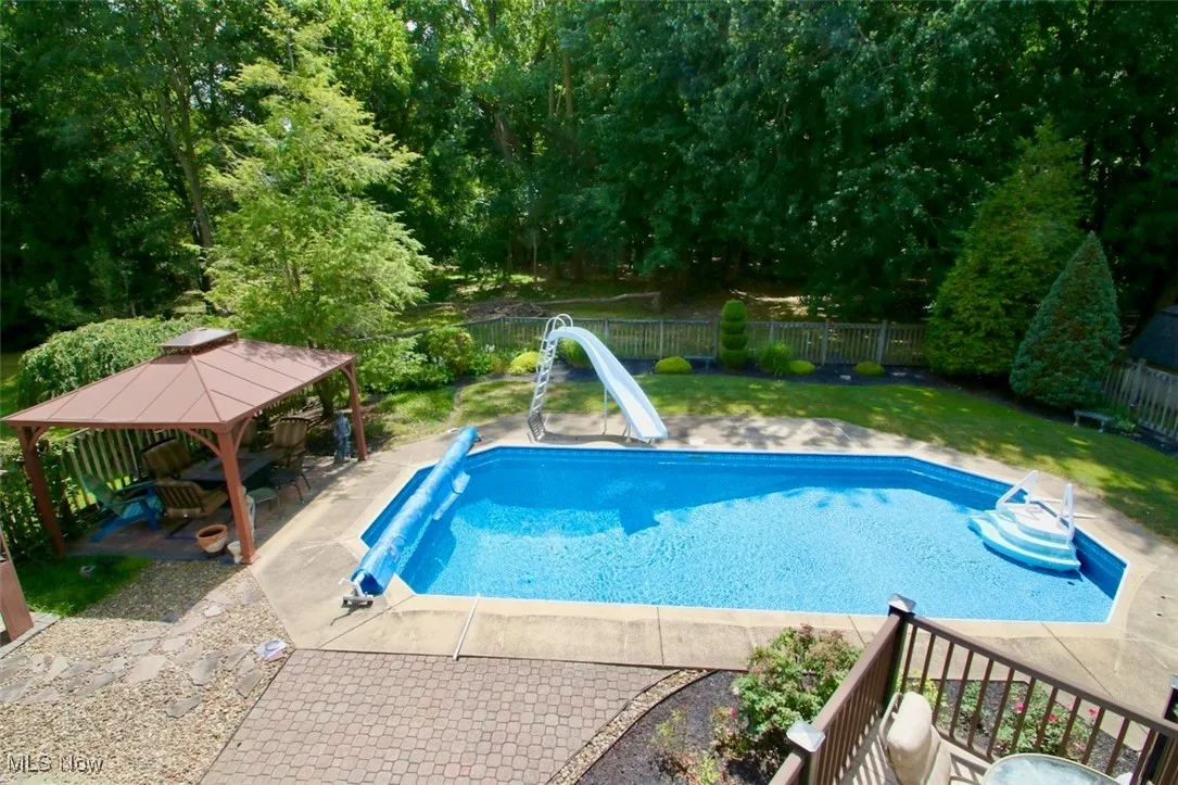 View of swimming pool featuring a patio, a gazebo, a water slide, and a fenced backyard