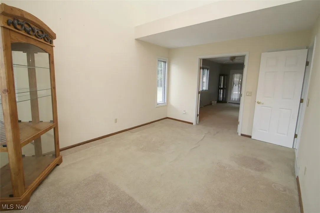 First floor den with light carpet facing front of home