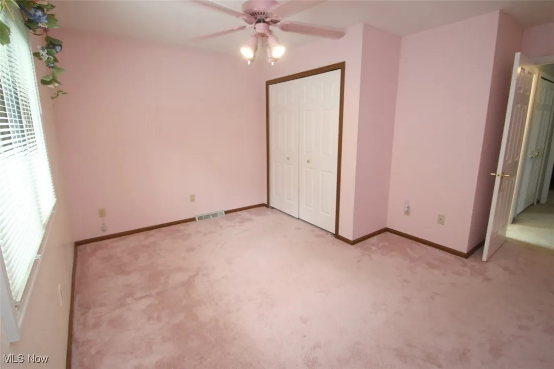 Unfurnished bedroom with light colored carpet, a closet, and ceiling fan