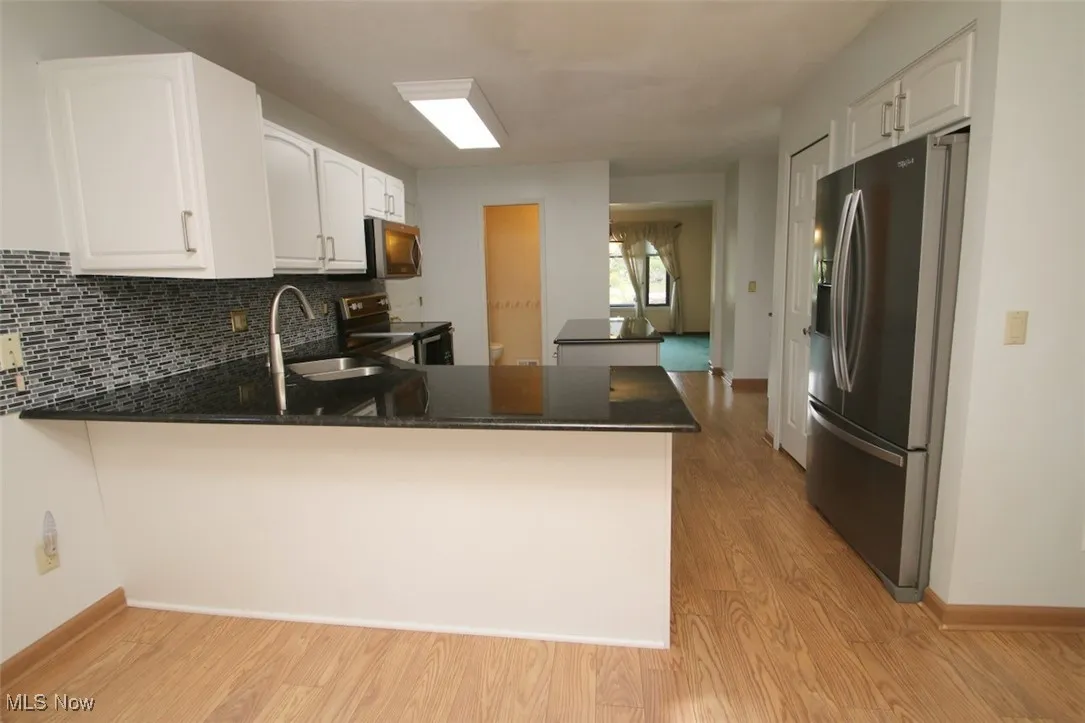 Kitchen featuring a peninsula, appliances with stainless steel finishes and decorative backsplash