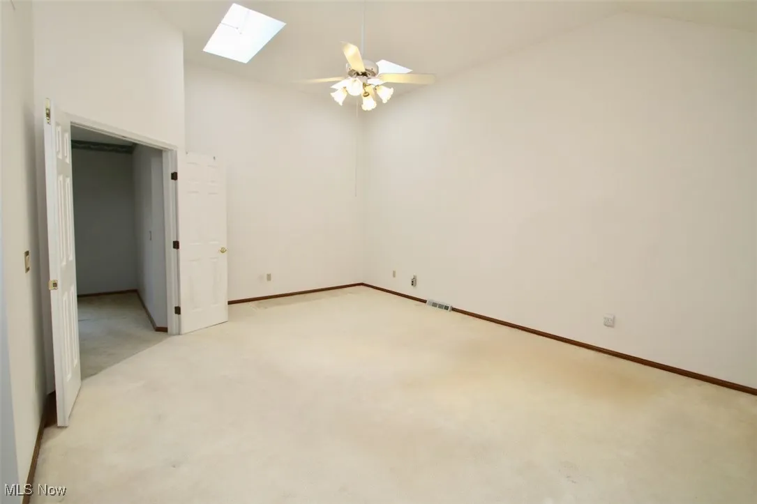 Master Bedroom, featuring a skylight, and doors to a small balcony, vaulted ceiling, and a ceiling fan