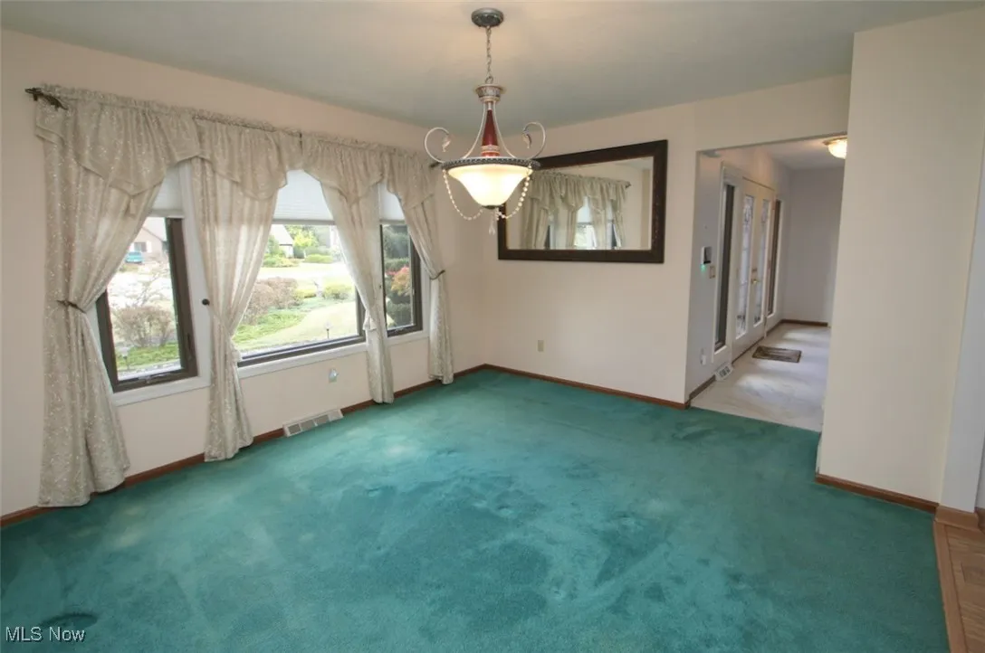 Unfurnished dining area featuring carpet flooring and baseboards