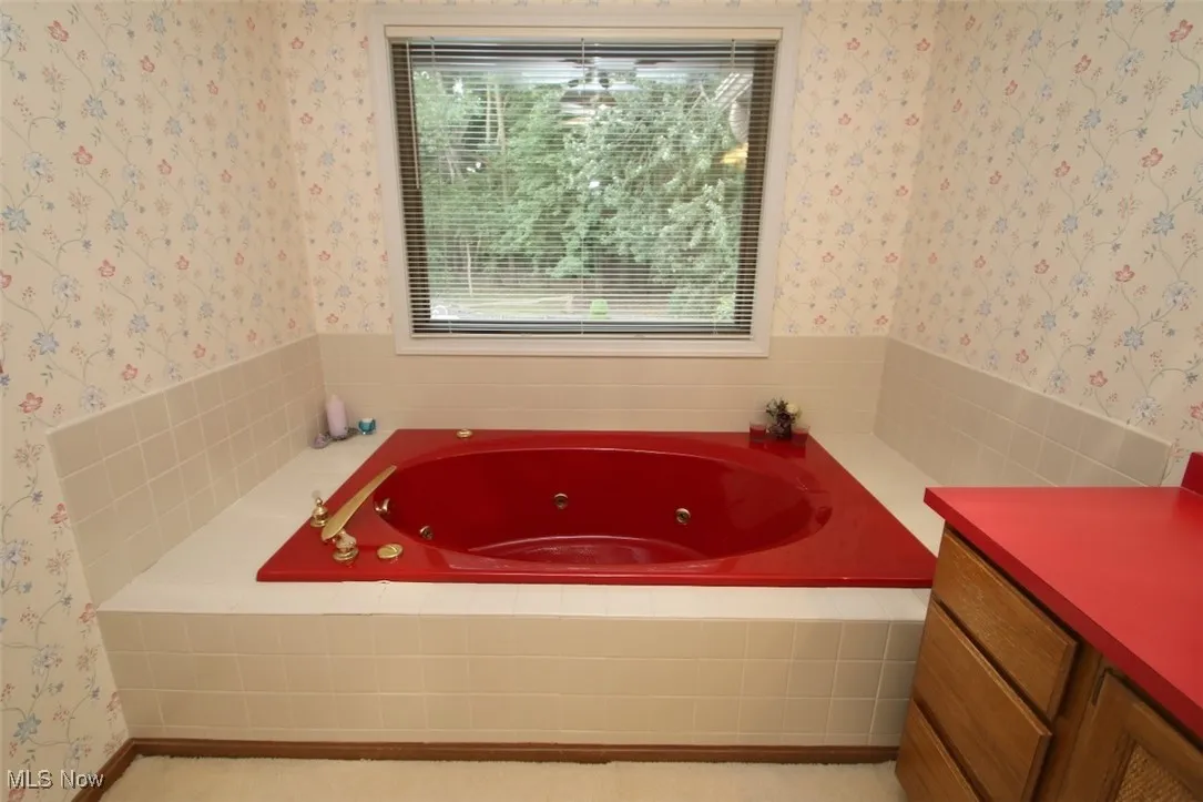 Full bathroom featuring a jetted tub and vanity