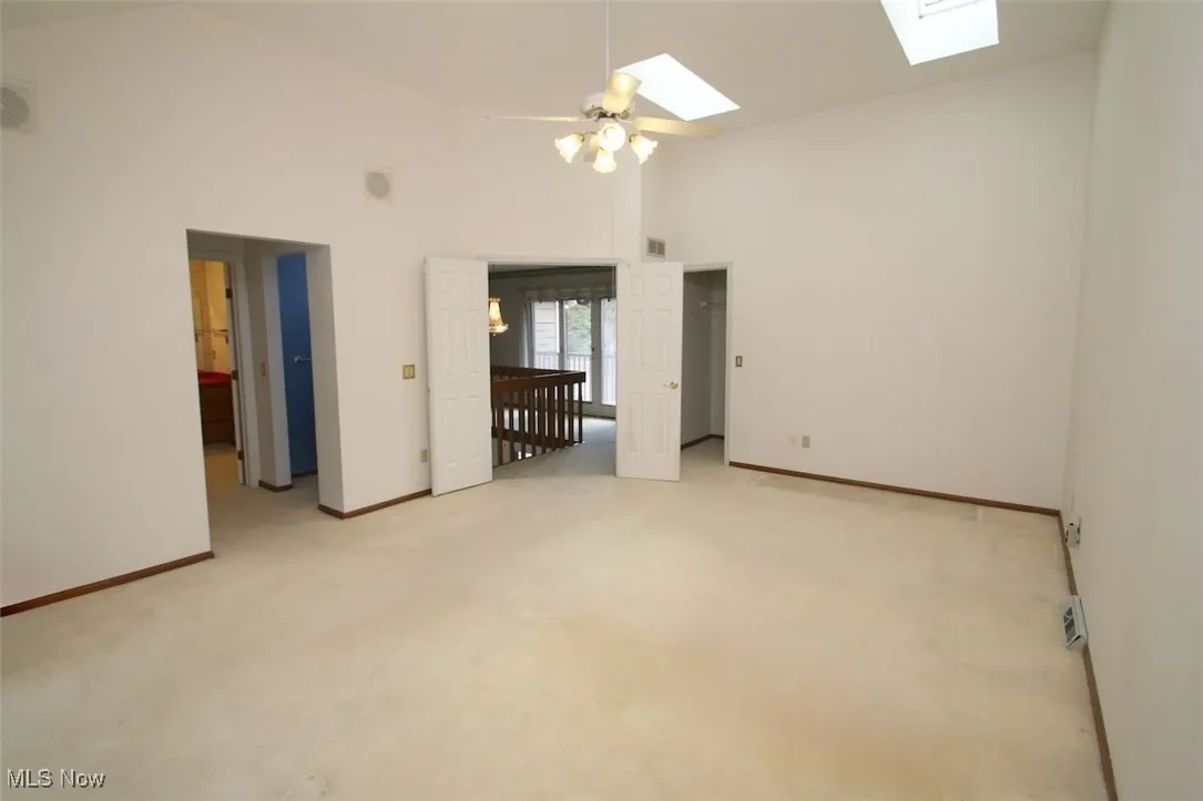 Master Bedroom featuring two skylights, high vaulted ceiling, light carpet, and ceiling fan