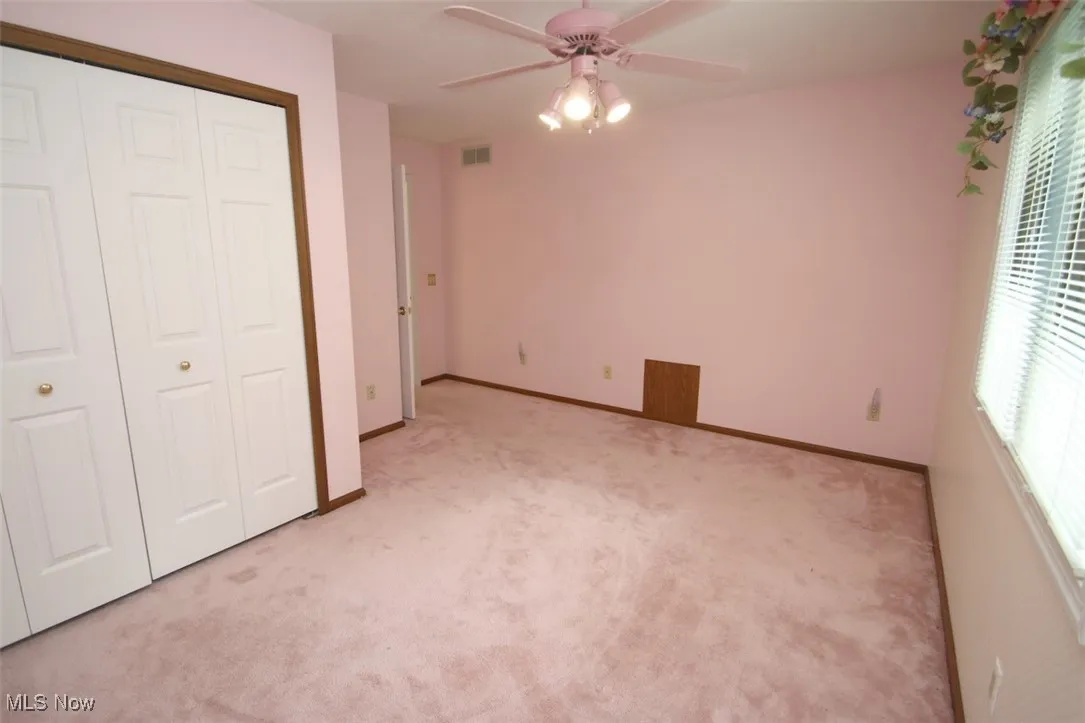 Unfurnished bedroom featuring light carpet, a closet, and ceiling fan