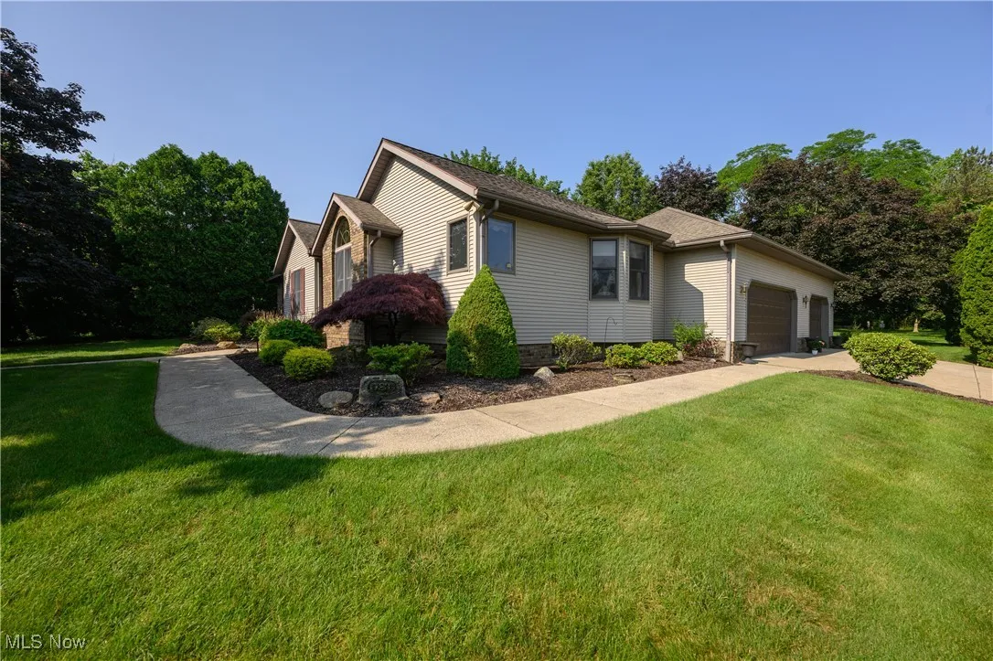 View of property exterior with a garage, a yard, concrete driveway, and view of wooded area