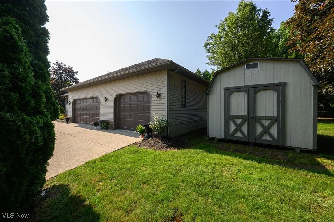 View of side of property with a yard, a garage, and a shed