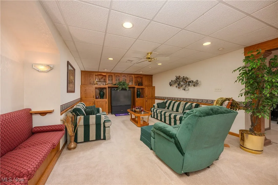 Living room featuring a drop ceiling, recessed lighting, carpet, and ceiling fan