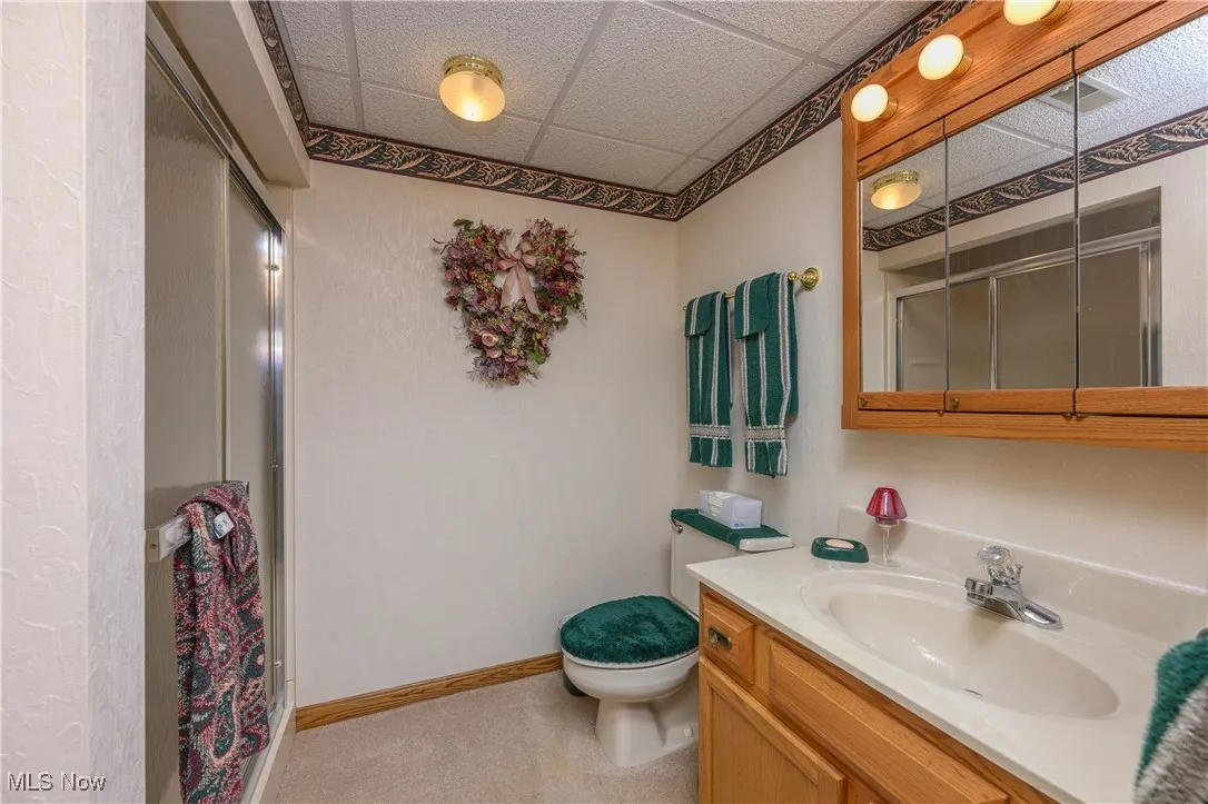 Full bath featuring vanity, a drop ceiling, and a stall shower