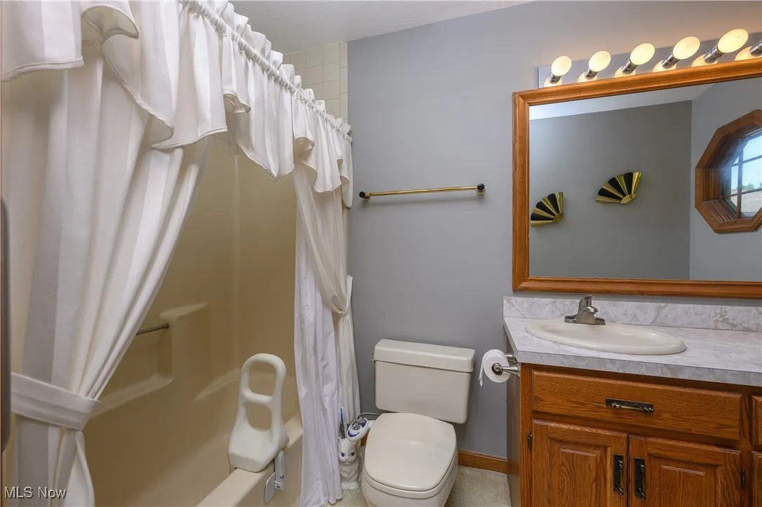 Bathroom with shower / bath combination with curtain and vanity
