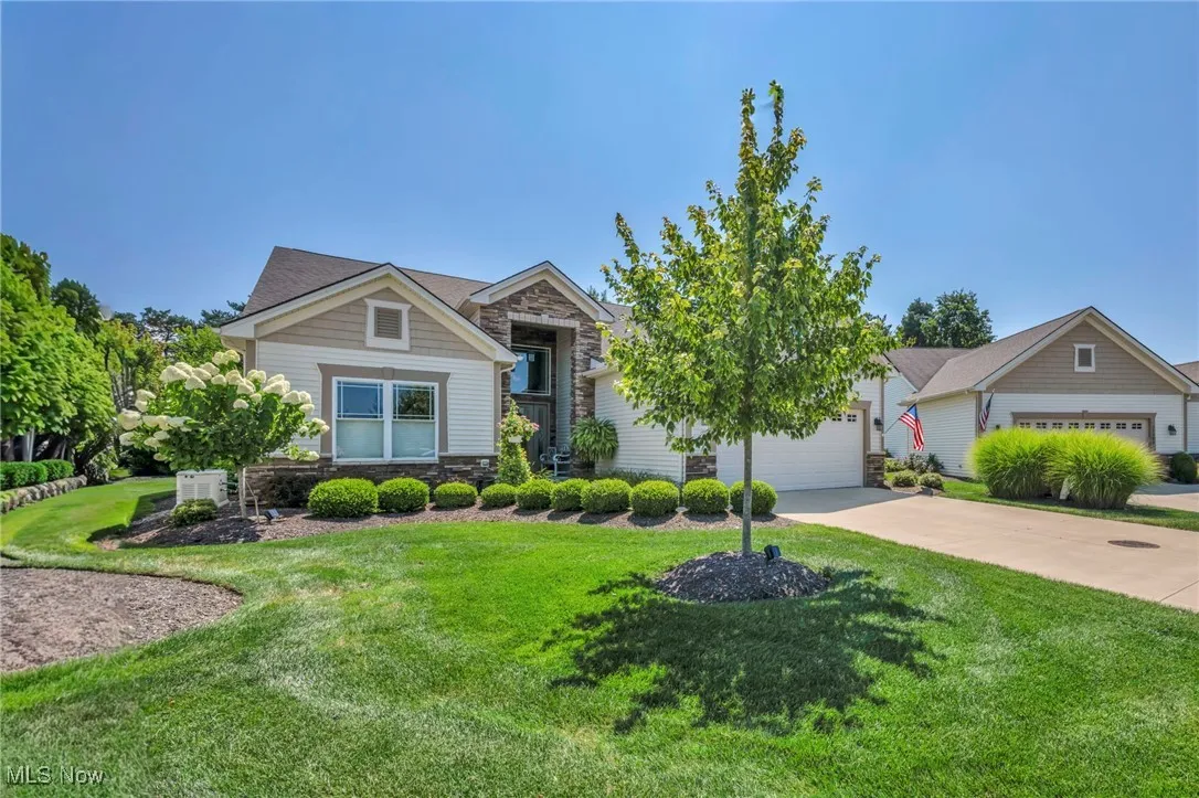 Craftsman-style home with stone siding, driveway, and a front yard