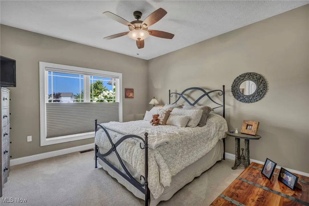 Bedroom with carpet floors, a ceiling fan, and a textured ceiling