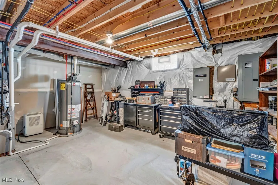 Below grade area featuring electric panel, Generator. a workshop area, and gas water heater